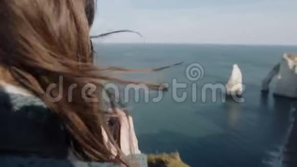 特写幸福自由摄影师女拍白Etretat岩石的照片头发在风中徐徐飘动视频的预览图