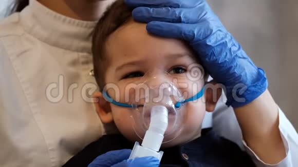 慢镜头肖像一个悲伤的小男孩戴着医疗面具医生轻轻抚摸着孩子头视频的预览图