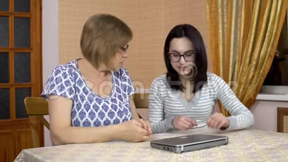 女儿教妈妈如何使用笔记本电脑一个年轻的女人展示了如何打开她老母亲笔记本电脑女人是视频的预览图