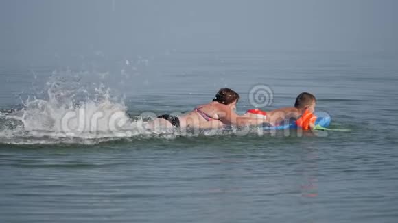 家庭在海上度假男孩在充气床垫上脚蹼在他们的手上冲浪那个女人视频的预览图