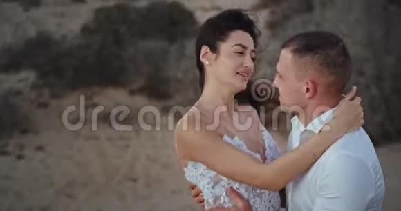微笑和幸福的夫妇穿着白色的衣服在惊人的中间拥抱着对方视频的预览图