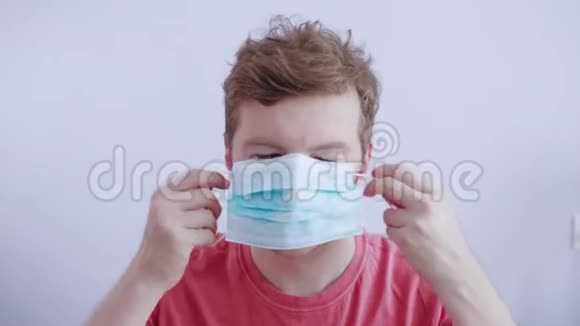 中年男子在白色工作室戴上一个保护性医疗面具以防止病毒和感染一个男人视频的预览图