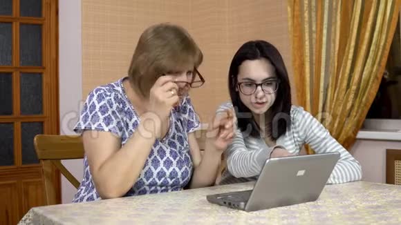 女儿教妈妈如何使用笔记本电脑一个年轻的女人告诉她的老母亲在哪里点击电脑那个女人视频的预览图