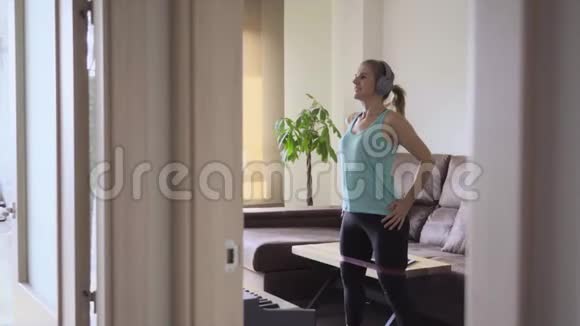 女人在家里的客厅里用弹性带做运动健康生活理念视频的预览图
