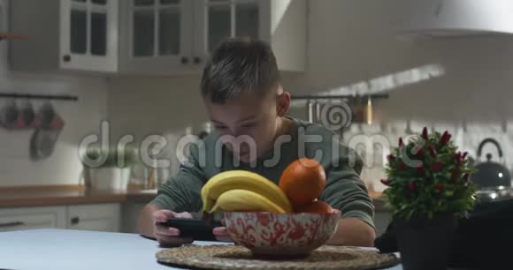 在厨房里玩智能手机的男孩视频的预览图