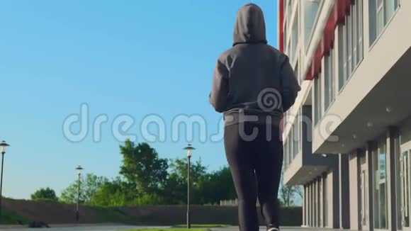 穿着连帽衫的女人早上在空城大街上奔跑视频的预览图
