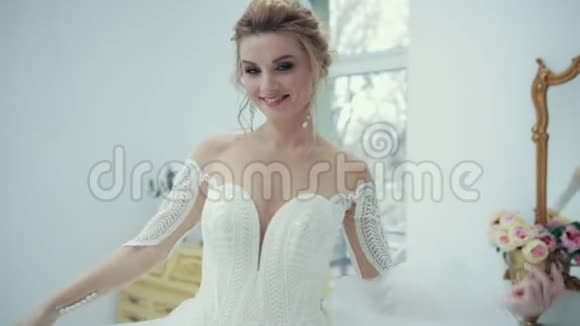 年轻的金发新娘穿着白色连衣裙微笑着摆着相机旋转视频的预览图