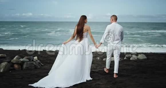 迷人的一对夫妇在迷人的风景和美丽的海滨他们走在一边牵手视频的预览图