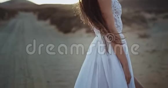 美丽的女士留着长发穿着婚纱在夕阳下美丽的景色中享受着时光视频的预览图