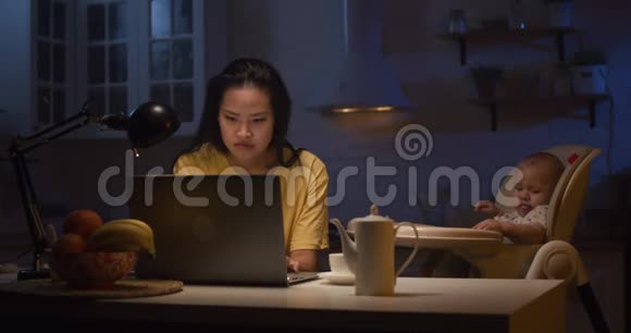 年轻妈妈带着孩子在手提电脑上工作视频的预览图