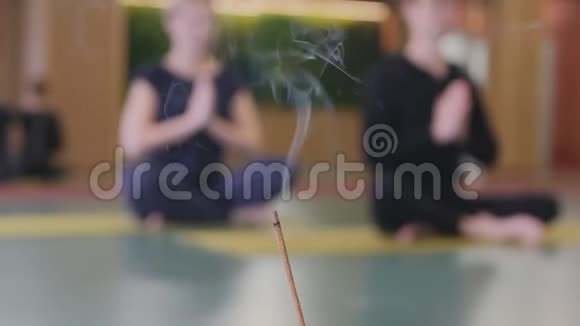 一根香棍在男人和女人冥想的背景下抽烟他们坐在地板上视频的预览图