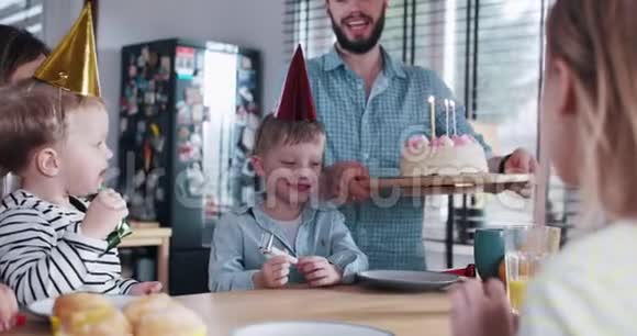快乐的小可爱白种人男孩吹生日蛋糕庆祝聚会在家与家庭慢动作视频的预览图