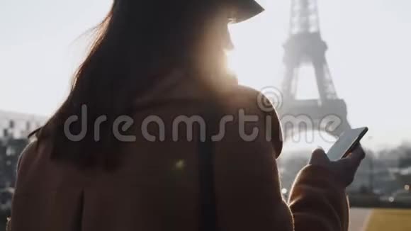 年轻漂亮的女商人使用电话信使应用程序行走在背光阳光下的巴黎埃菲尔铁塔观景慢运动视频的预览图