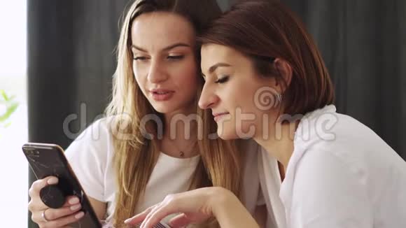 两个年轻的女人用智能手机在网上商店里选择东西视频的预览图