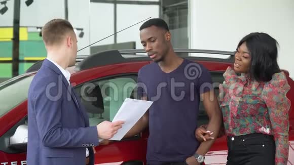年轻英俊的汽车销售商向他在汽车经销店的非裔美国顾客解释了一些事情汽车生意汽车视频的预览图