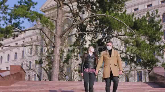 一对戴着防护面罩的夫妇走在镜头前的街道上他们手里拿着新概念视频的预览图