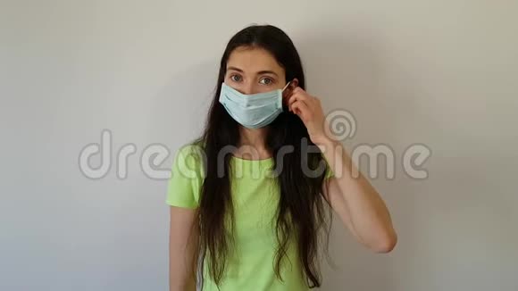 那个黑发女人从脸上摘下了保护性的医疗面具微笑着病人的康复快乐的女孩在家视频的预览图