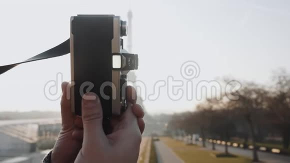 特写摄影师手拍一张背光日落巴黎埃菲尔铁塔的照片配上老式电影相机慢镜头视频的预览图