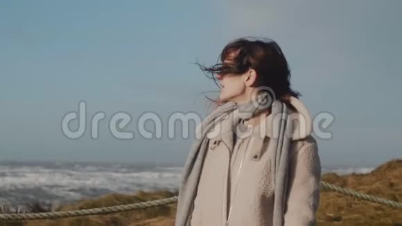 快乐美丽微笑的白人旅游妇女的肖像双臂伸展在冬天的海边慢动作视频的预览图
