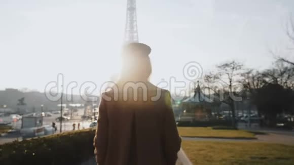 镜头跟随快乐轻松的美丽女人在巴黎缓慢的运动中沿着背光的阳光秋埃菲尔铁塔行走视频的预览图