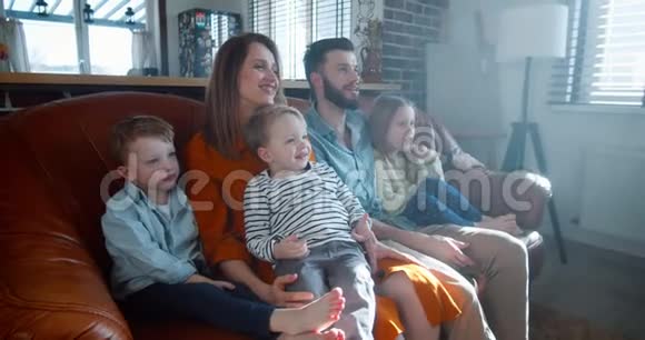 团结的概念幸福的欧洲家庭与三个可爱的孩子在家里看有趣的卡通沙发慢动作视频的预览图