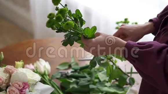 女花匠在制作花束特写镜头时从叶子上清理植物的茎视频的预览图