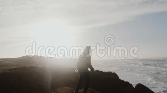 在阳光明媚的冬天海上悬崖风光下坚强的男子站在极端狂风暴雨下的背影慢镜头视频的预览图