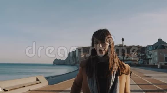 美丽快乐的欧洲旅游妇女走向相机微笑沿着阳光明媚的海滩在埃特雷塔诺曼迪慢动作视频的预览图