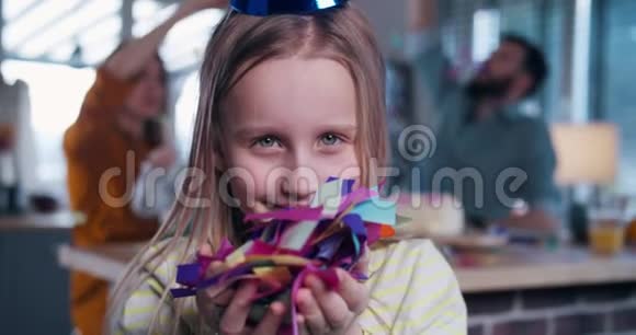 可爱快乐710岁的女孩吹着纸屑在相机微笑庆祝生日聚会与家庭慢动作视频的预览图