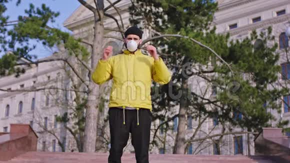 一个穿着黄色夹克衫的年轻人在空荡荡的街道上的镜头前这个人拿着他的保护装置感到高兴视频的预览图