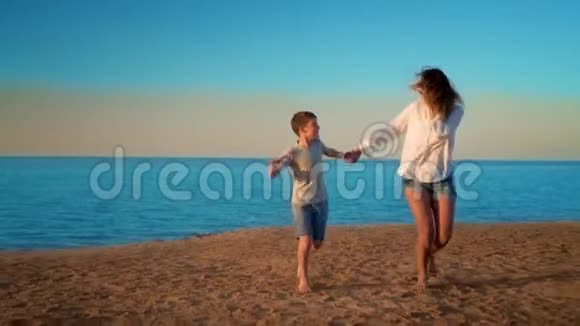母亲和儿子靠手在海边奔跑视频的预览图