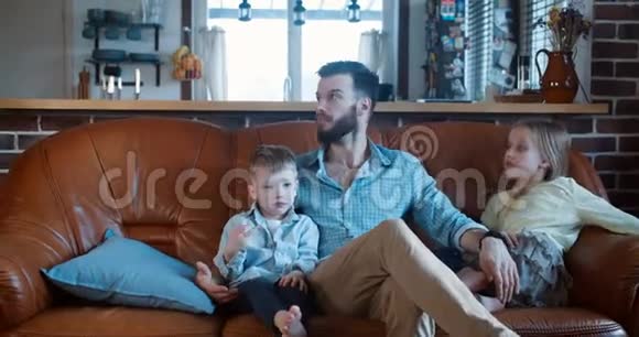 家庭时间在家年轻的高加索父母和三个孩子坐在一起玩看电影慢动作视频的预览图