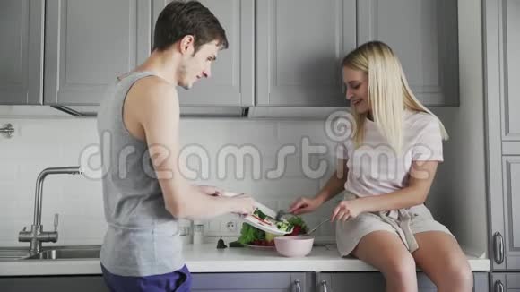 年轻人和女孩坐在桌子上一起切蔬菜做沙拉在厨房吃午饭视频的预览图
