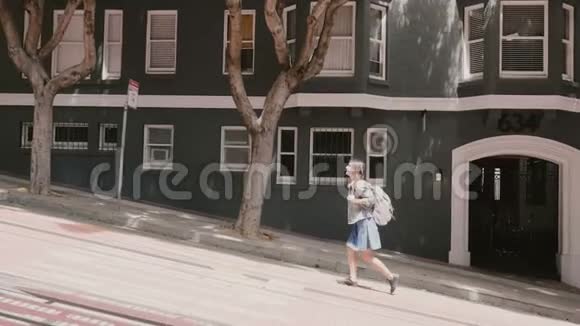 在美国旧金山夏天一位带着背包走在非常陡峭的街道上的快乐微笑的年轻旅游妇女视频的预览图