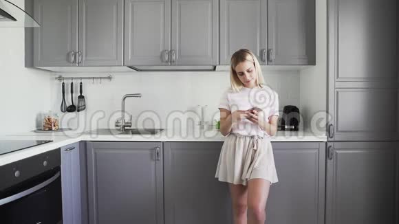 早上在厨房检查电话的小女孩女人用手机和朋友聊天女孩在打短信视频的预览图
