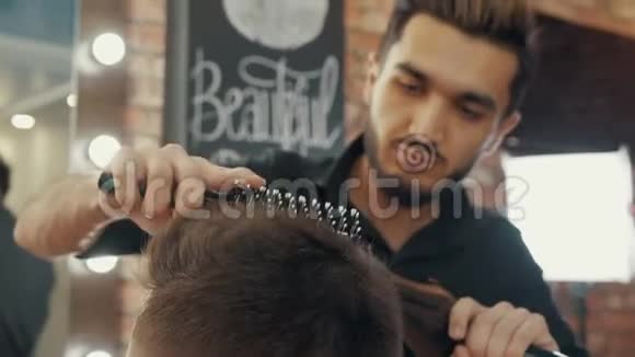 理发师用吹风机和刷子在男性沙龙烘干客户头发发型师用烘干机做发型视频的预览图