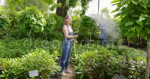 花园里的男人和女人站在一起在花上喷水视频的预览图