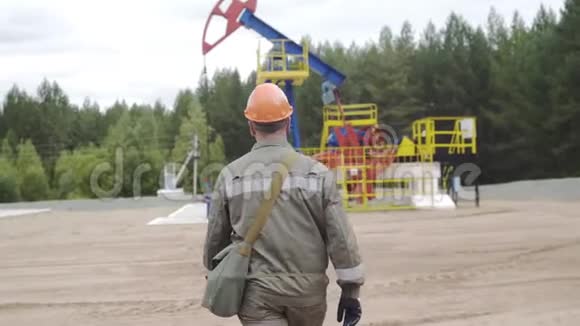 跟随射击油工步行到油田的油泵千斤顶平衡驱动杆泵油摇杆抽取原油视频的预览图
