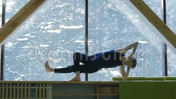 大窗户背景上的瑜伽一个年轻可爱的家伙做运动来增强肌肉窗外是视频的预览图