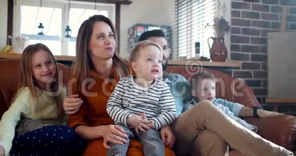 快乐的家庭时光在一起年轻的白种人父母和三个孩子在家看电影慢动作视频的预览图