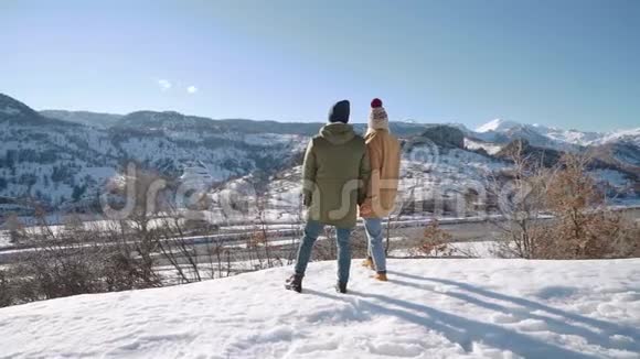 年轻夫妇站在雪山上望着群山视频的预览图