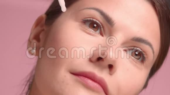 30岁的黑发女人穿着粉色背景的完美皮肤装饰上衣视频的预览图