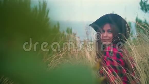一个长发女孩的肖像穿着黑色和红色的衬衫戴着牛仔帽坐在干草里视频的预览图