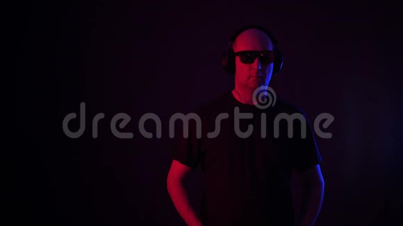 男人在黑色背景下听耳机中的移动音乐秃头男用耳机欣赏音乐视频的预览图