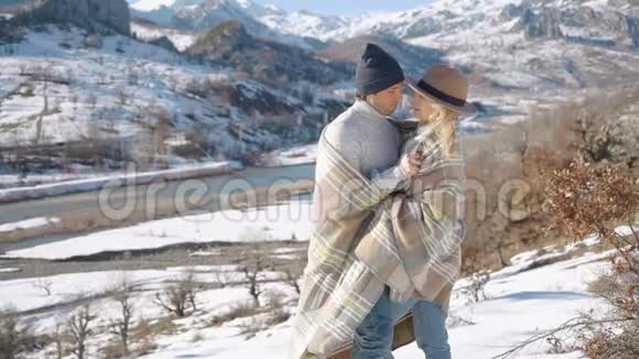 这对年轻夫妇在美丽的雪山背景下拥抱亲吻视频的预览图