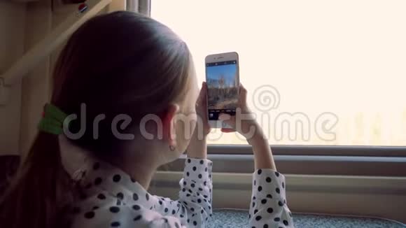 可爱的少女在智能手机直通车窗口拍摄大自然视频的预览图