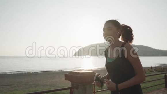 日落时分在海滨慢跑在海边奔跑的女孩视频的预览图