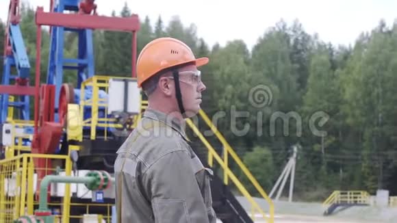 石油工人监督原油生产现场的慢镜头工业油泵千斤顶工作和抽油视频的预览图