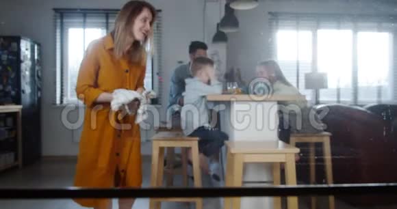 波夫拍摄的年轻快乐的白种人妇女带着热杯蛋糕走出烤箱以庆祝节日与家庭慢动作视频的预览图