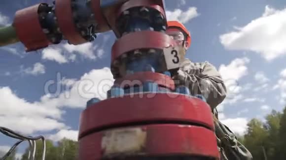 油工在橙色安全帽和防护玻璃开或关阀的x质量井口关闭井交叉交叉交叉视频的预览图